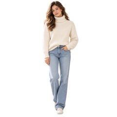 A woman modeling a cream ribbed turtleneck sweater and light-wash blue jeans against a plain white background.