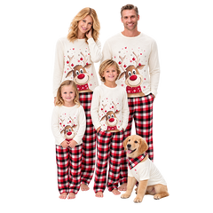 A family of four and a dog wearing matching Christmas pajamas against a solid white background. The pajamas feature a white long-sleeve top with a red and white reindeer graphic, paired with red and black plaid pants.